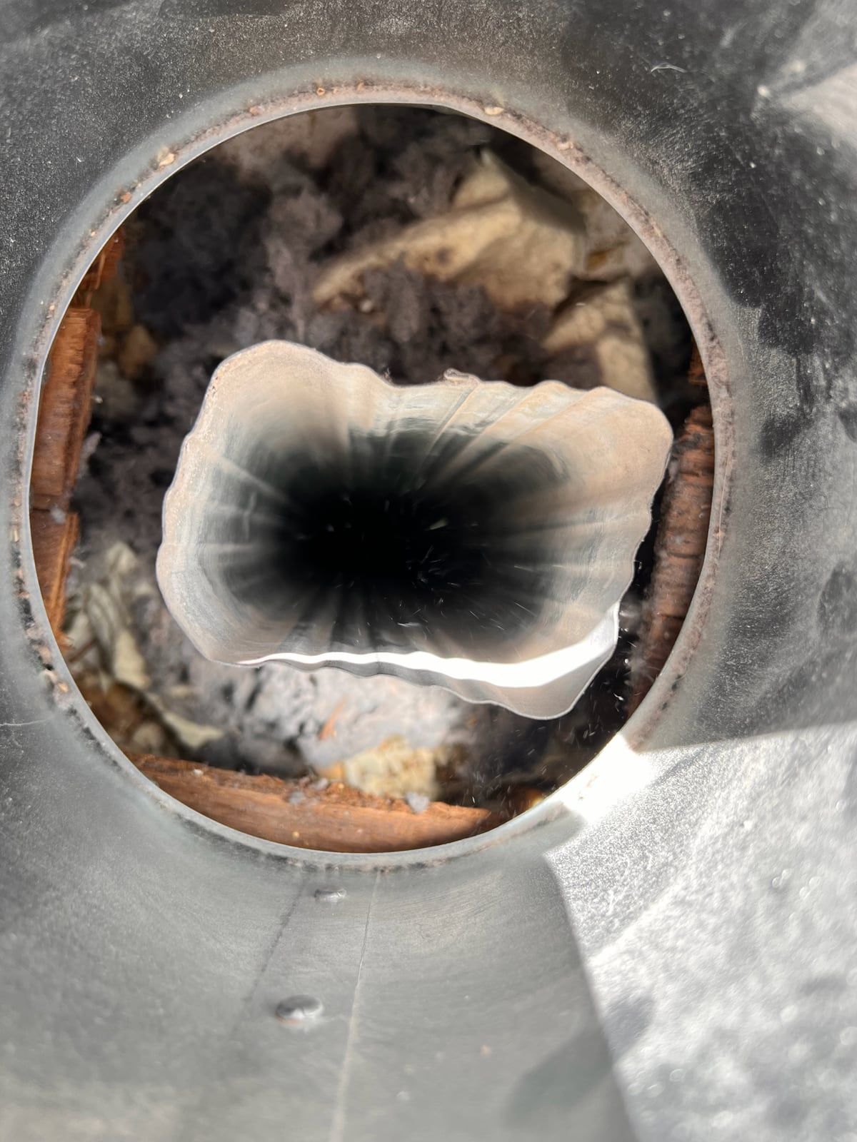 The same dryer duct opening after cleaning, with clean metal walls and a clear airway