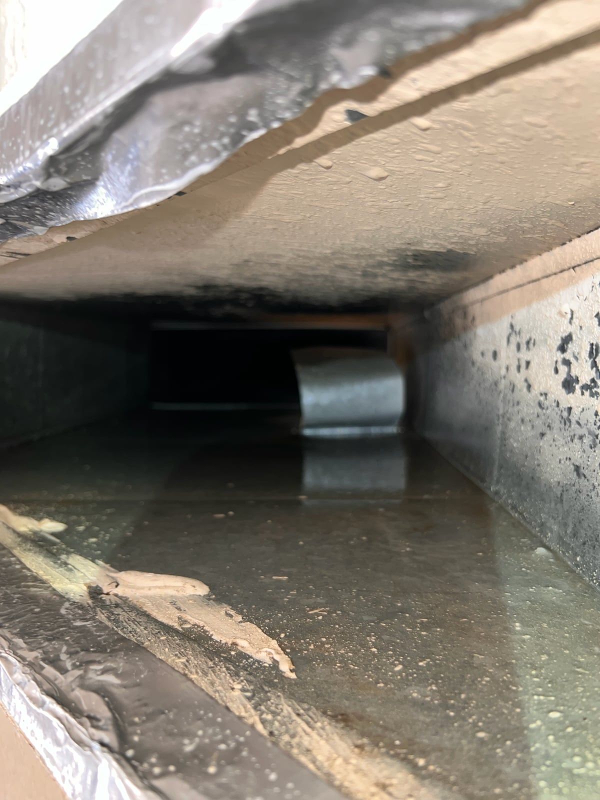 The same supply trunk after cleaning, with the floor of the duct clear and reflective