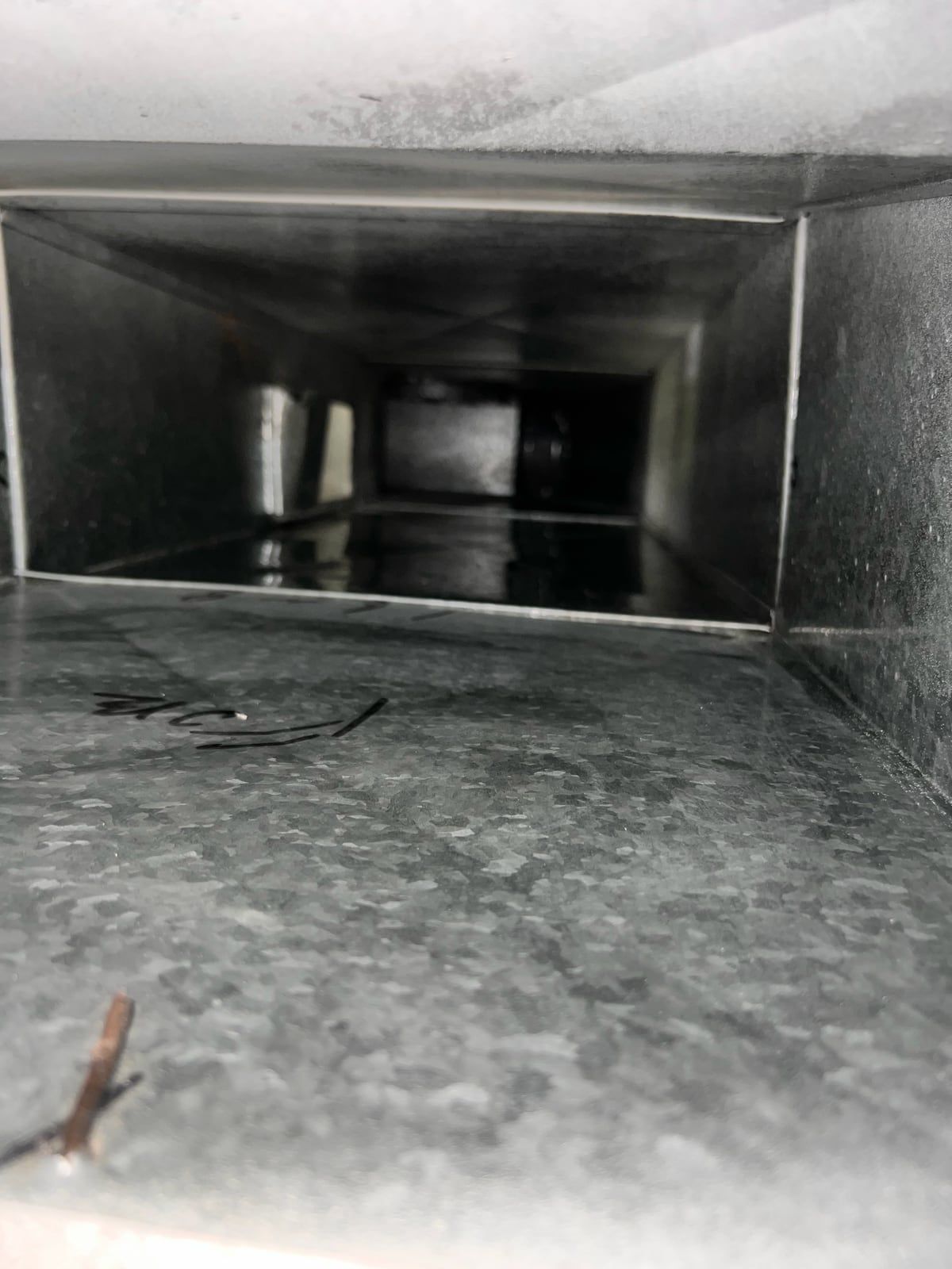 The same supply trunk after cleaning, with bright galvanized metal showing along its length