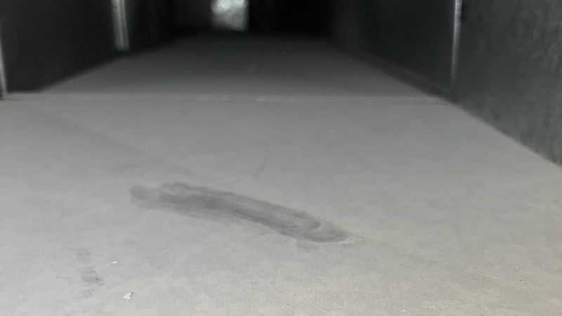Inside a long supply trunk before cleaning, gray with dust, with a dark streak wiped through it