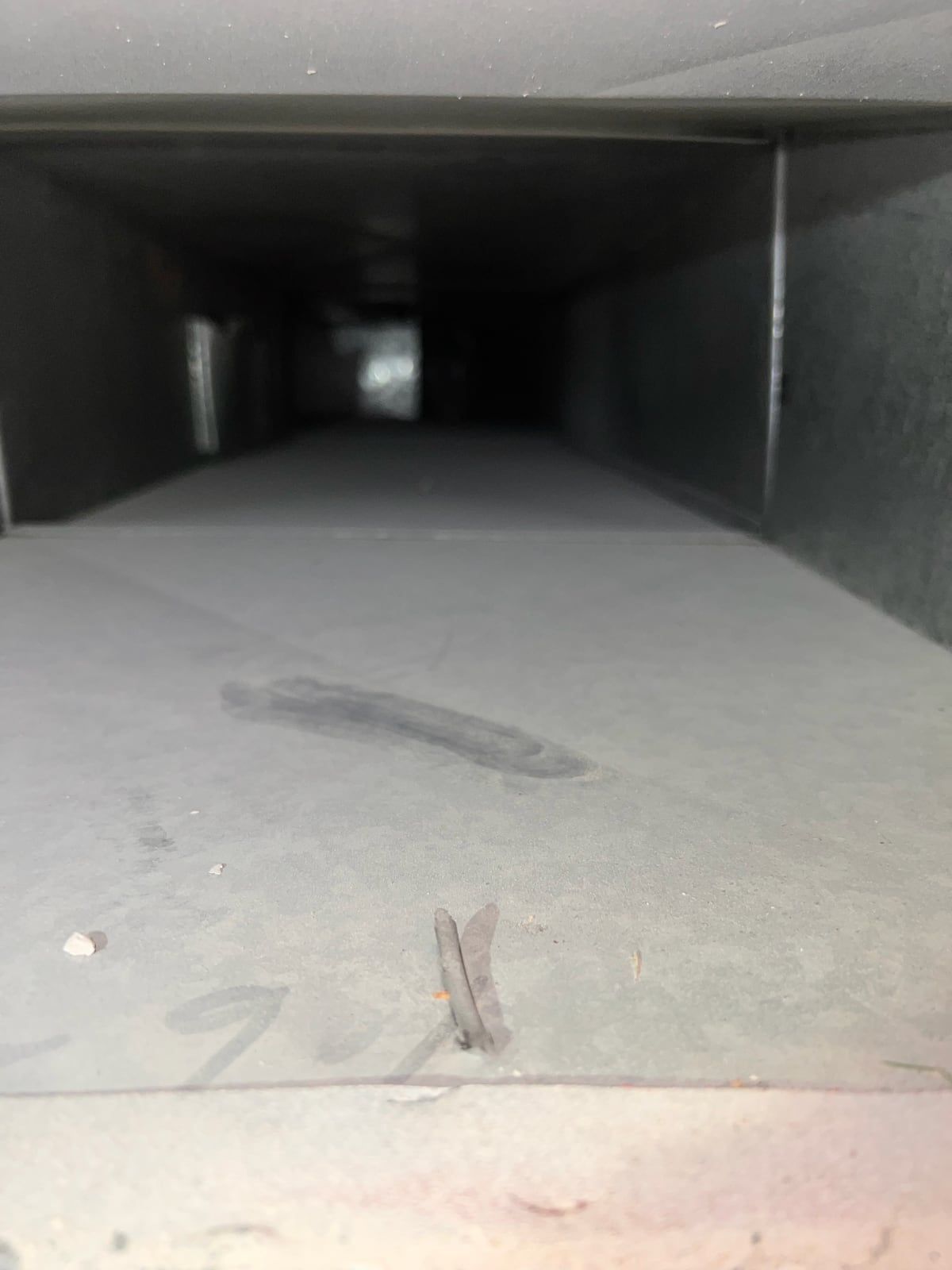 Inside a long supply trunk before cleaning, gray with dust, with a dark streak wiped through it