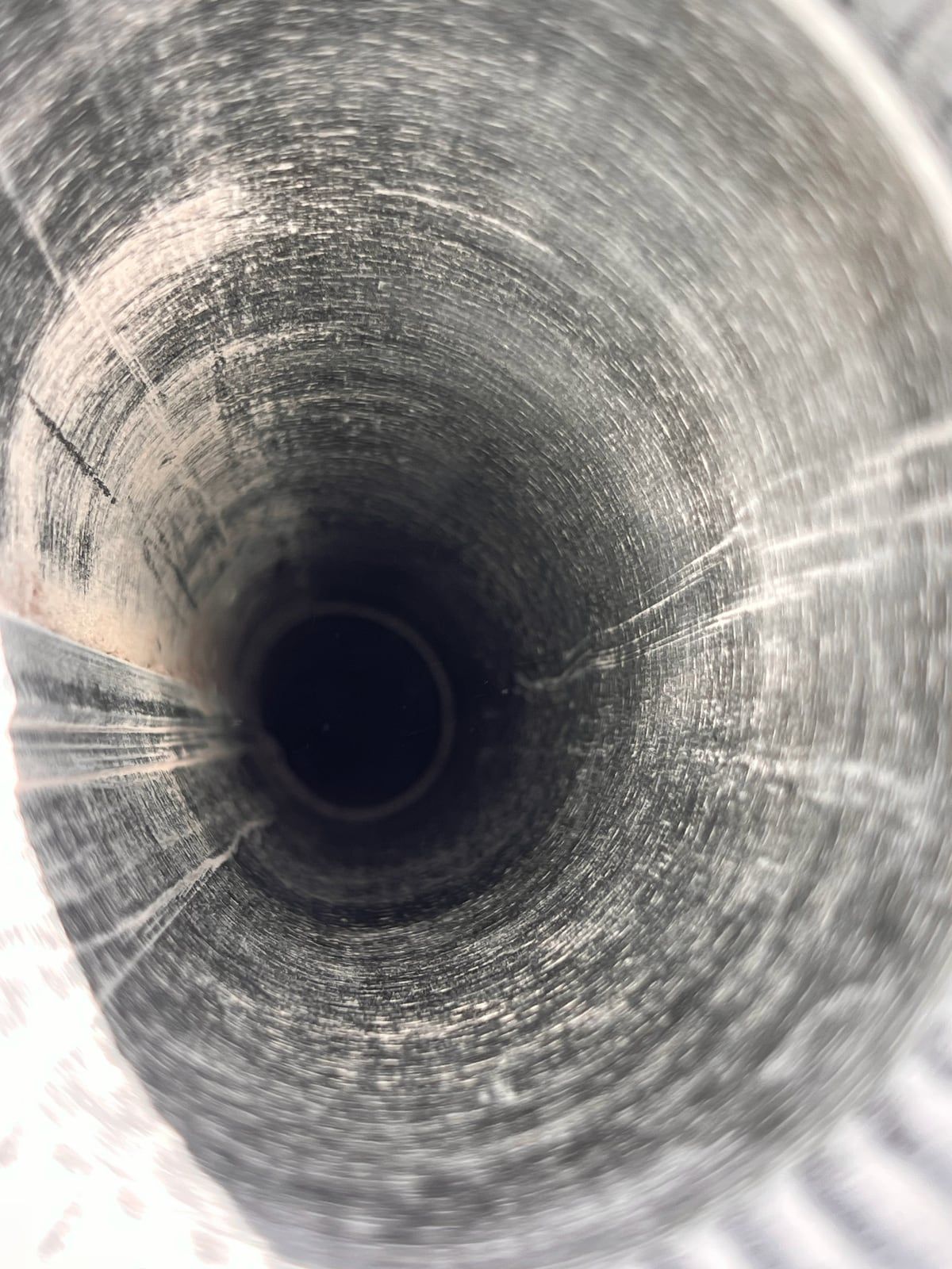 The same dryer duct after brushing, with bare metal walls and an open airway